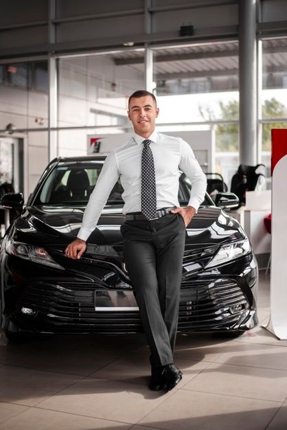 Concesionario de automóviles de ángulo bajo, apoyándose en el automóvil | Foto Premium